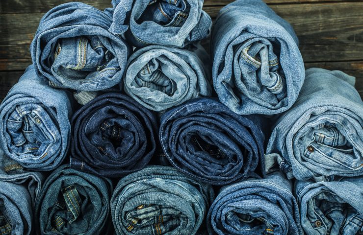 bunch of jeans twisted on a wooden background, fashionable clothes